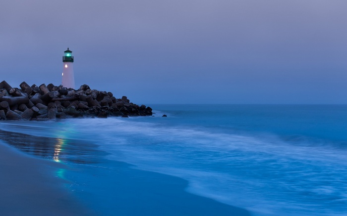 Lighthouse on a rocky shore at dusk