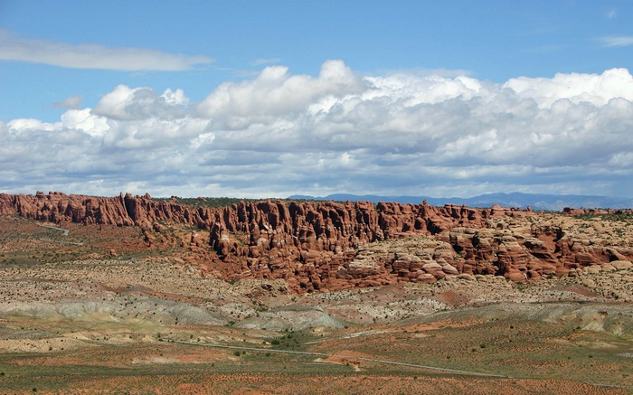 Desert landscape with red rock formations and clouds