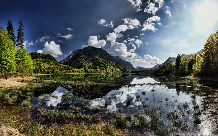 Mountain lake reflection with trees and clouds