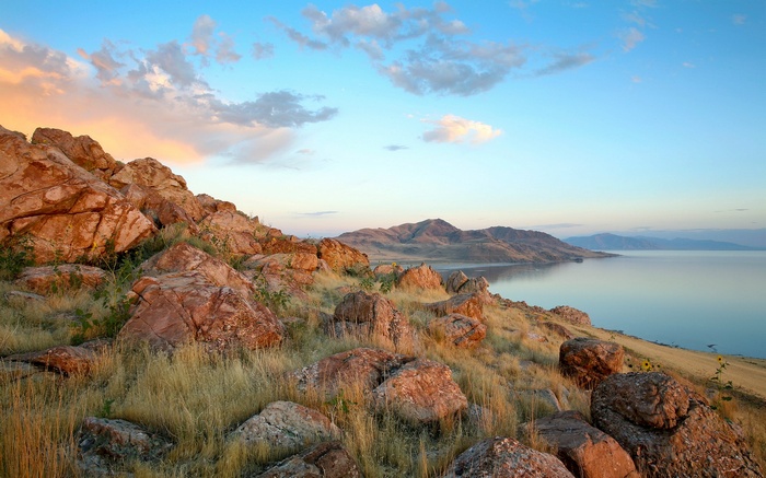 Rocky shoreline overlooking a calm lake at sunset