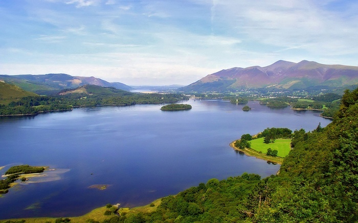 Lake surrounded by mountains and trees under a cloudy sky