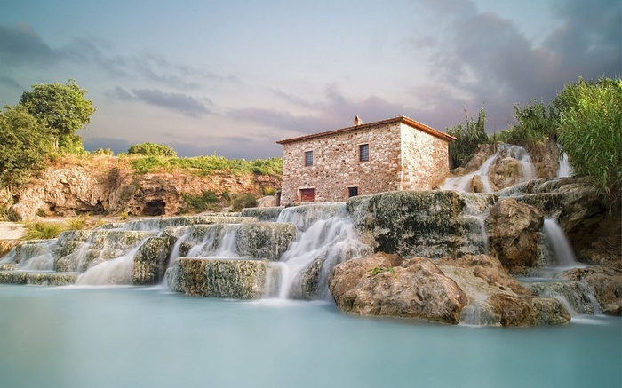 Stone building by cascading waterfalls