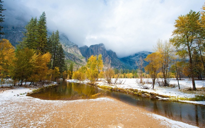 River flowing through a snowy forest with mountains