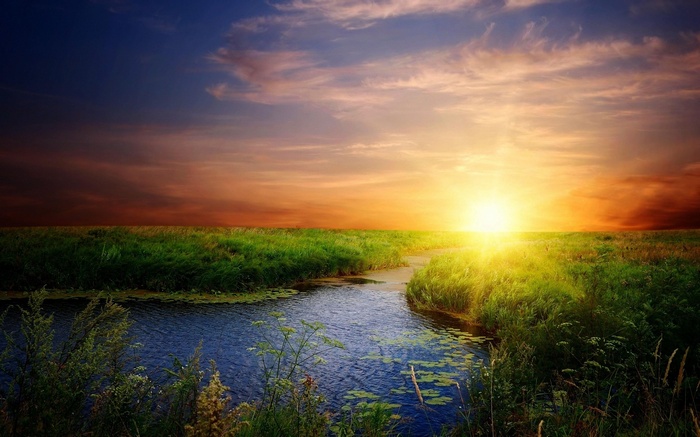 Sunset over a river and grassy field