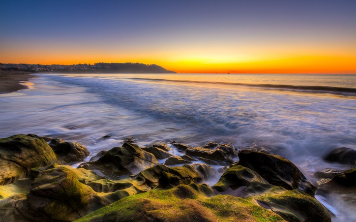 Ocean waves crash on rocky shore at sunset