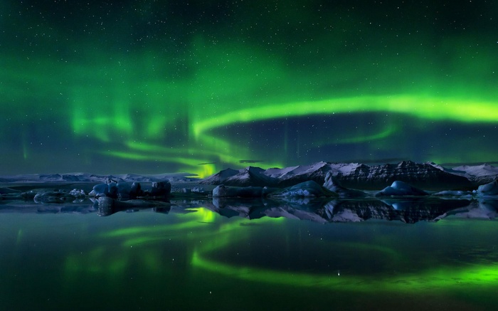 Aurora Borealis over icy lake and mountains