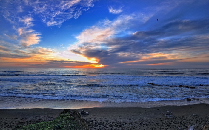 Sunset over the ocean with waves and clouds