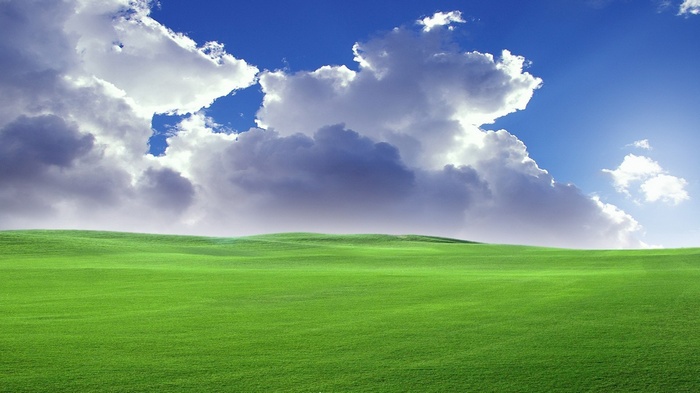 Green rolling hills under a cloudy blue sky