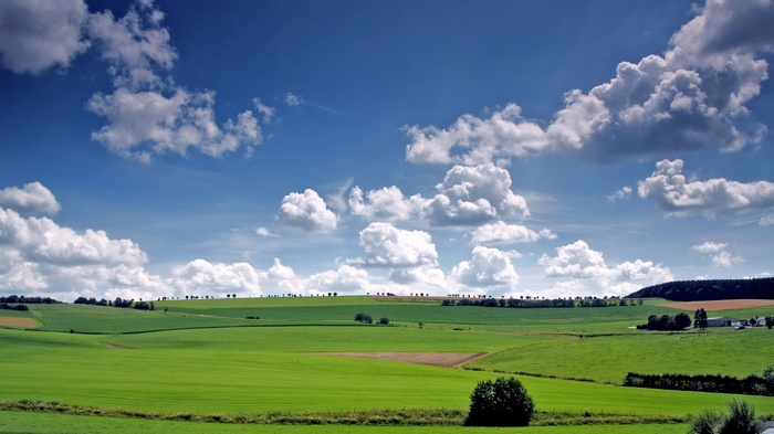 Rolling green hills under a blue sky with clouds