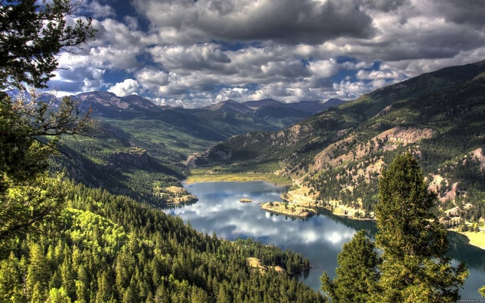 Mountain lake surrounded by pine forests under a cloudy sky