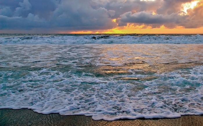 Ocean waves crashing on a beach at sunset