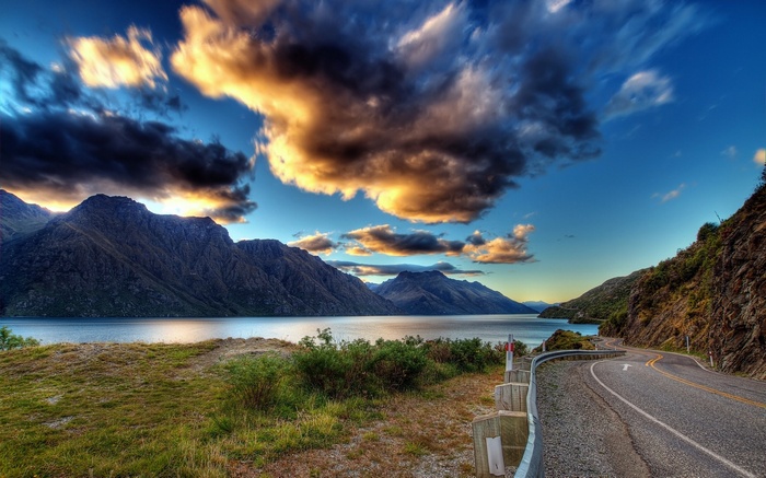 Mountain lake with winding road and dramatic clouds