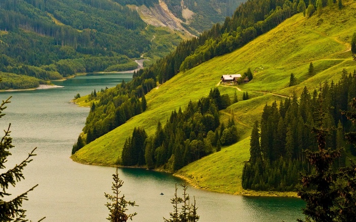 A house on a green hillside overlooking a lake