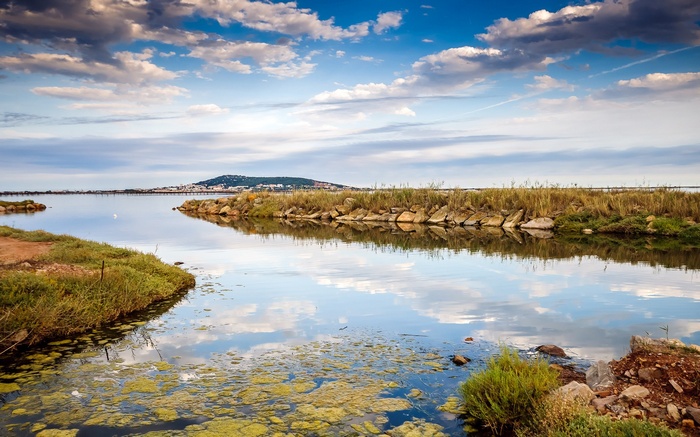 Calm lake with distant town and cloudy sky