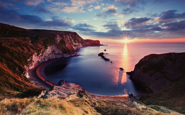 Sunrise over a rocky coastline and calm sea