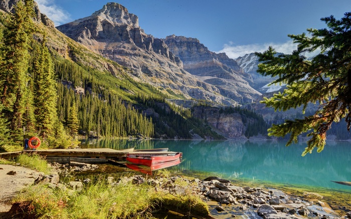 Red canoe on a wooden dock by a mountain lake