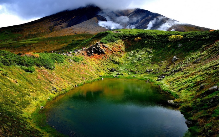Crater lake with steaming mountain in the background