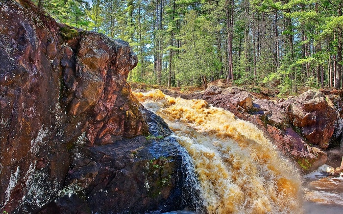 Brown waterfall cascading over rocks in a forest