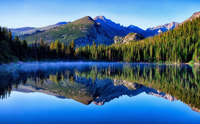 Mountain lake reflection with pine trees and mountains