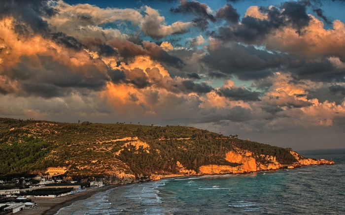 Coastal cliffs and beach at sunset with dramatic clouds