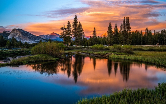Mountain lake reflecting sunset sky and trees