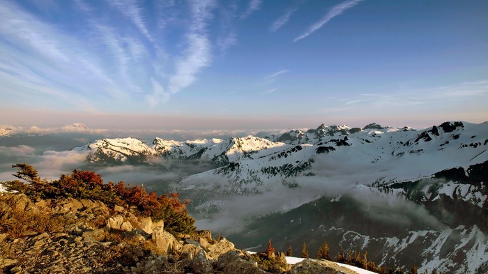 Snow-capped mountains under a cloudy blue sky