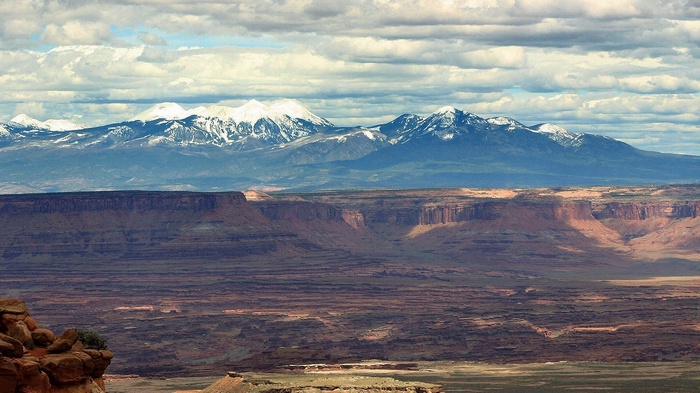 Snow-capped mountains over a desert canyon landscape