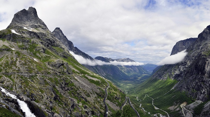 Winding road through a mountain valley with clouds