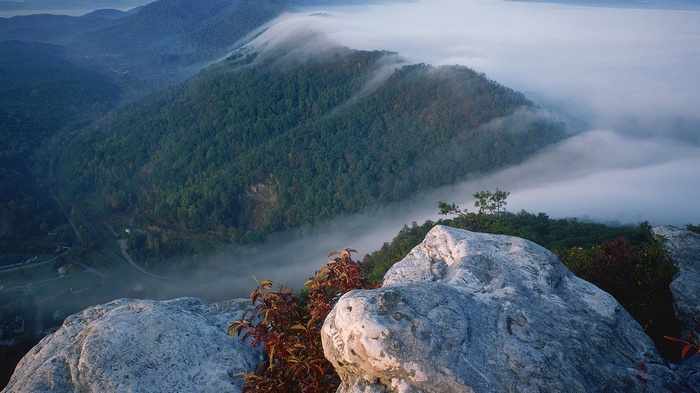 Foggy mountain valley with rocky foreground