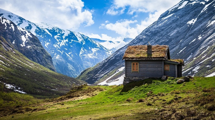 Wooden cabin with grass roof in a mountain valley