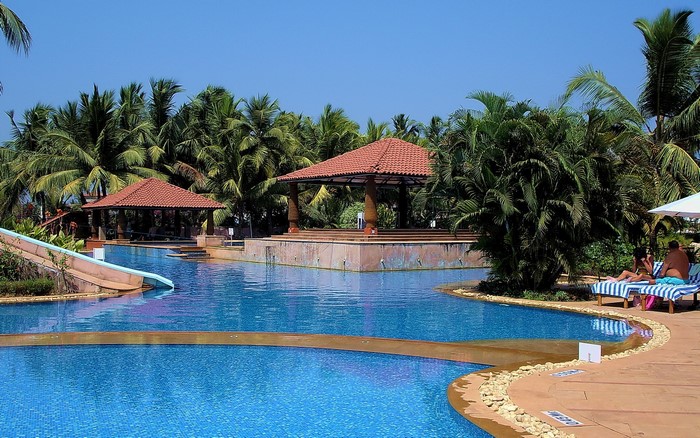 Resort swimming pool with palm trees and gazebos