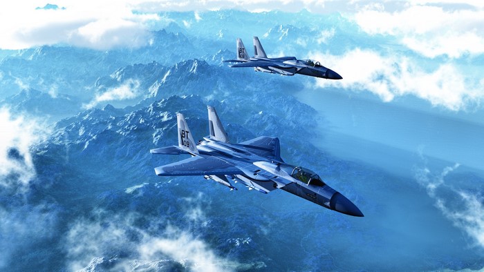 Two F-15 fighter jets flying over mountains