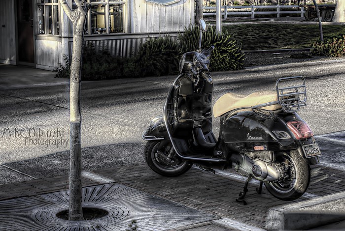 Black Vespa Scooter on Sidewalk