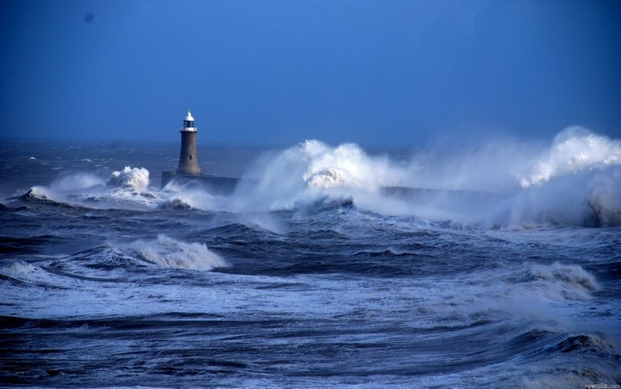 Stormy seas crash against a lighthouse pier