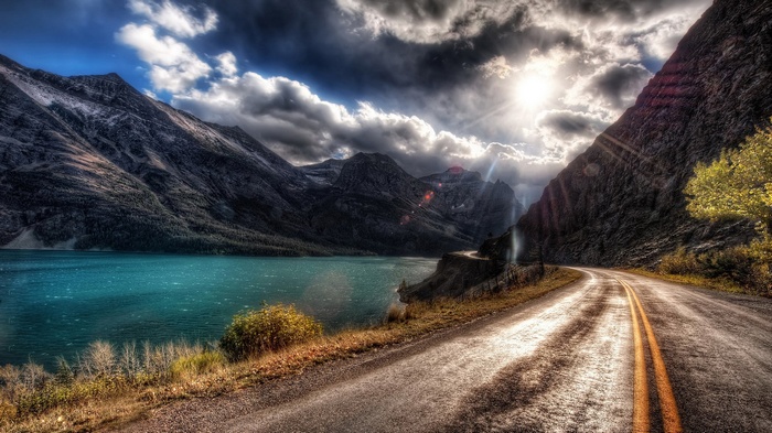 Mountain road next to a turquoise lake
