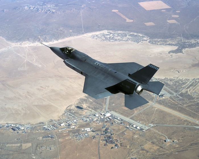 F-35 fighter jet flying over desert landscape