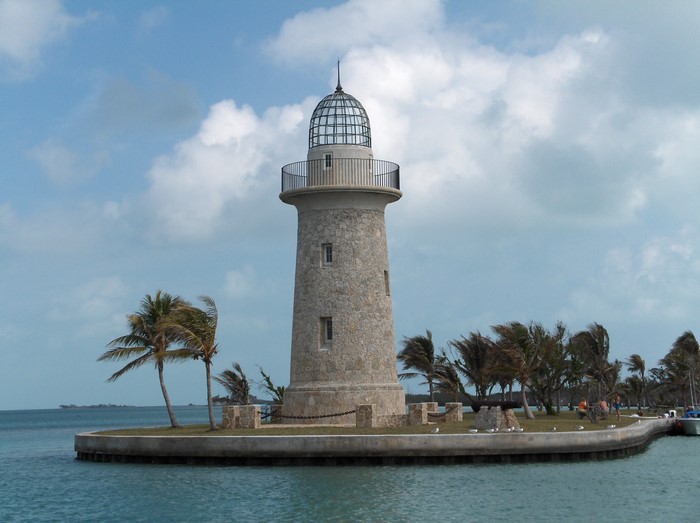 Stone lighthouse on a small island with palm trees