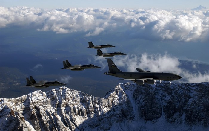 US Air Force F-15 fighter jets and KC-135 tanker fly over mountains