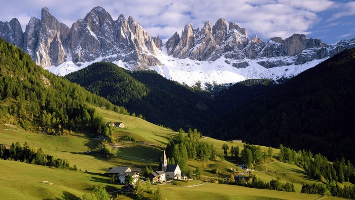 Snow-capped mountains above a green valley with a village