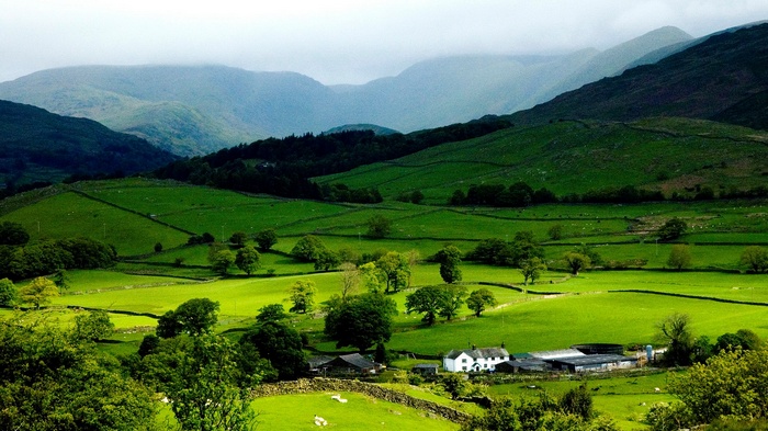 Green rolling hills with a farm and mountains