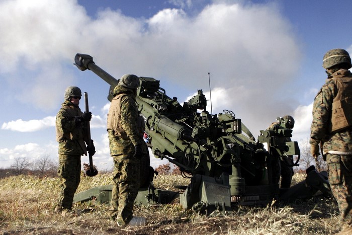 Marines operate a large artillery cannon in a field