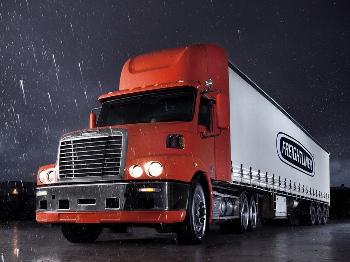 Freightliner semi-truck driving in the rain at night