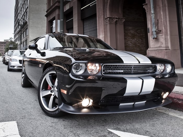 Black Dodge Challenger with white stripes parked on street
