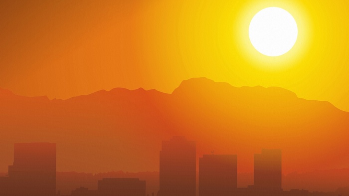 City skyline at sunset with mountains and sun