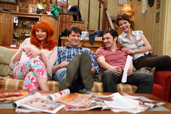 Four people sitting on a couch in a living room