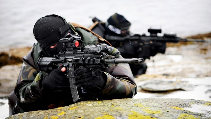 Soldiers aiming rifles in a rocky, cold environment