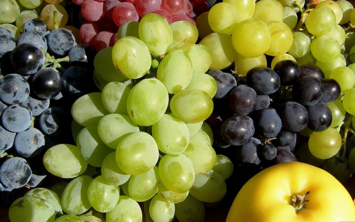 Assortment of Grapes and a Yellow Apple