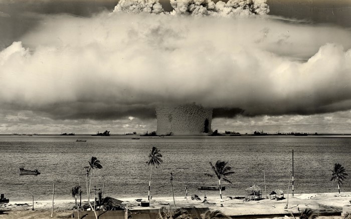 Nuclear explosion over the ocean with ships and palm trees
