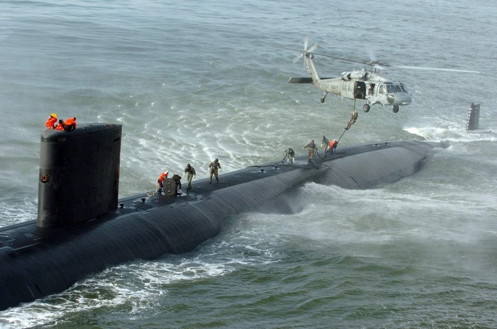 Helicopter transfers personnel to a submarine at sea
