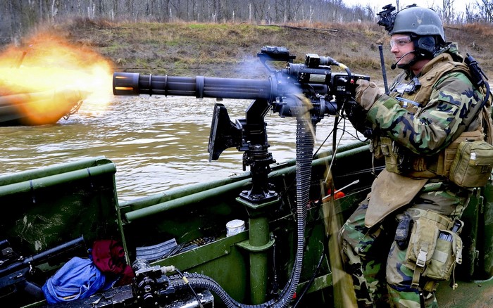 Soldier firing a Gatling gun from a boat